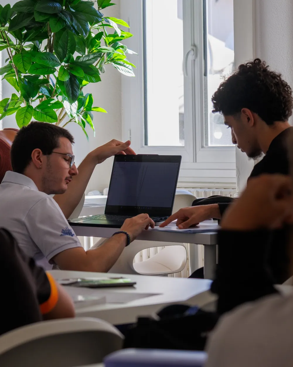 An SOS mentor works with a gymnase student on his laptop, at the centre